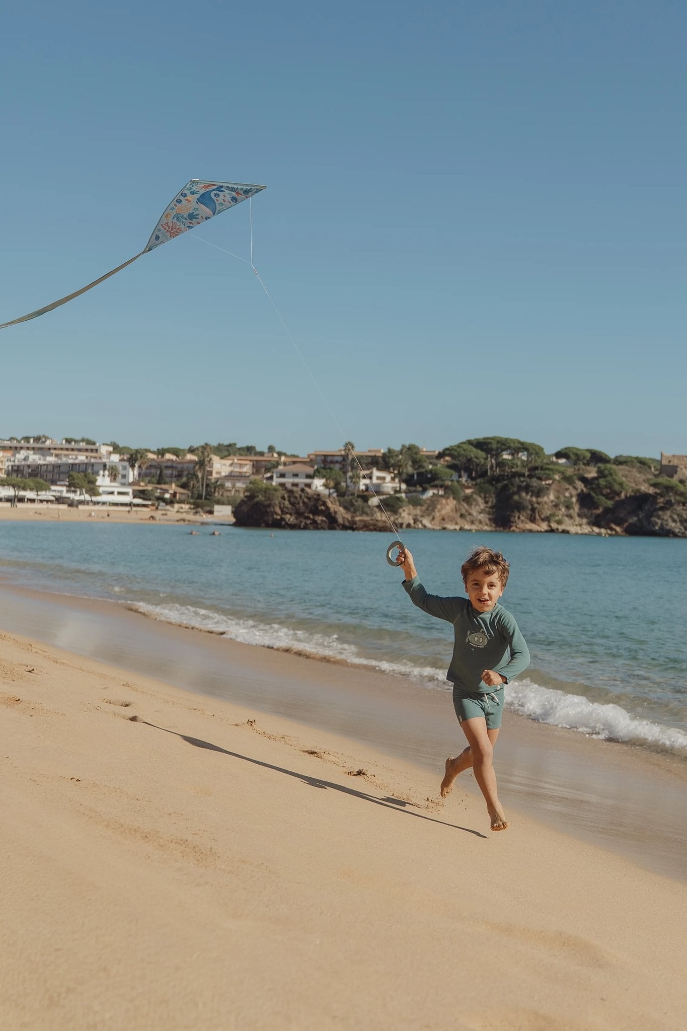 Kind rennt mit Drachen am Meer entlang von Little Dutch